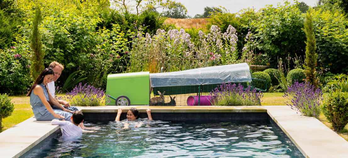 Una famiglia che gioca in una piscina all'aperto davanti alla conigliera Eglu Go .