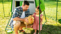 Uomo con la figlia che tiene in mano una gallina in un pollaio