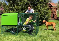 Signora, ragazzo, cane e loro Omlet verde Eglu Cube grande pollaio e corsa
