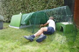 Una persona che dimostra come pulire una pista per conigli collegata a una conigliera verde