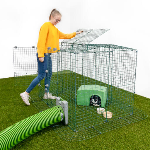 Una ragazza che apre una sezione di una pista per animali con conigli all'interno in un rifugio con una pista Zippi 