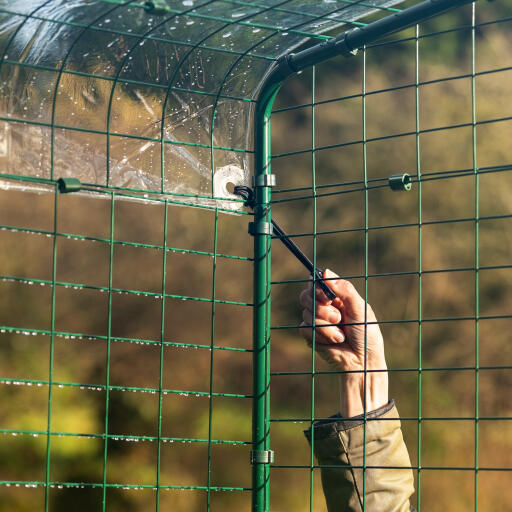 Una mano che fissa la copertura alla pedana mobile con ganci bungee