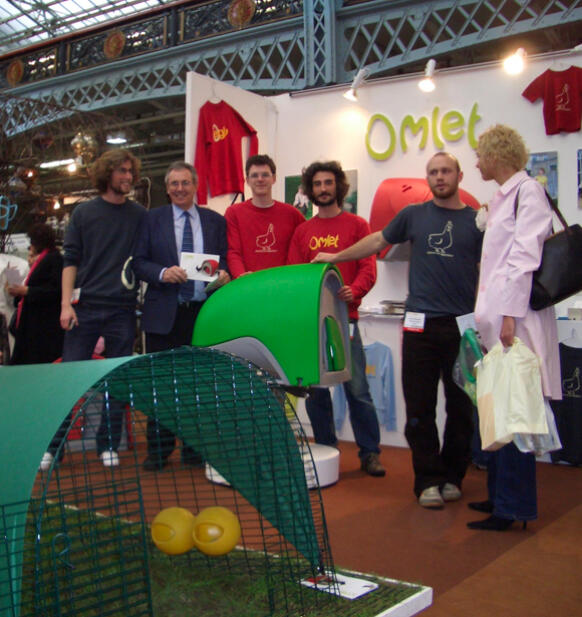 Un gruppo di persone in posa presso uno stand con il pollaio Eglu Cube 