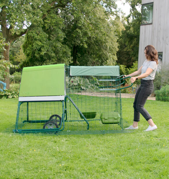 Donna che sposta il suo pollaio portatile Eglu Go ip nel giardino di casa