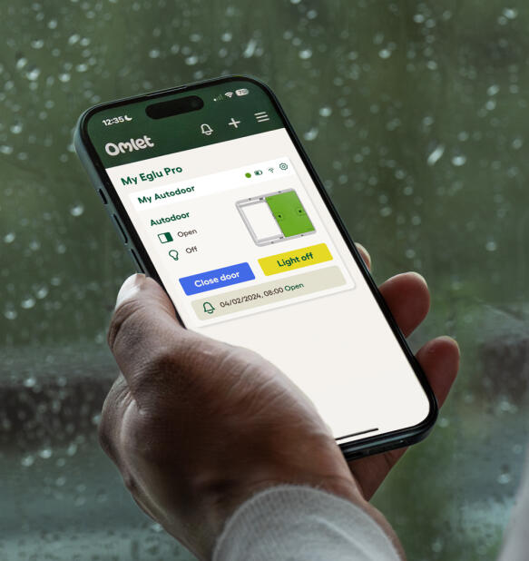 Mano che regge un telefono con l'applicazione Omlet smart Autodoor aperta