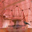 Un uccello modello appollaiato su una mangiatoia all'interno di una gabbia per uccelli rosa con uno specchio