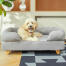Cane seduto su Topology letto per cani con bolster sormontato e piedi in legno