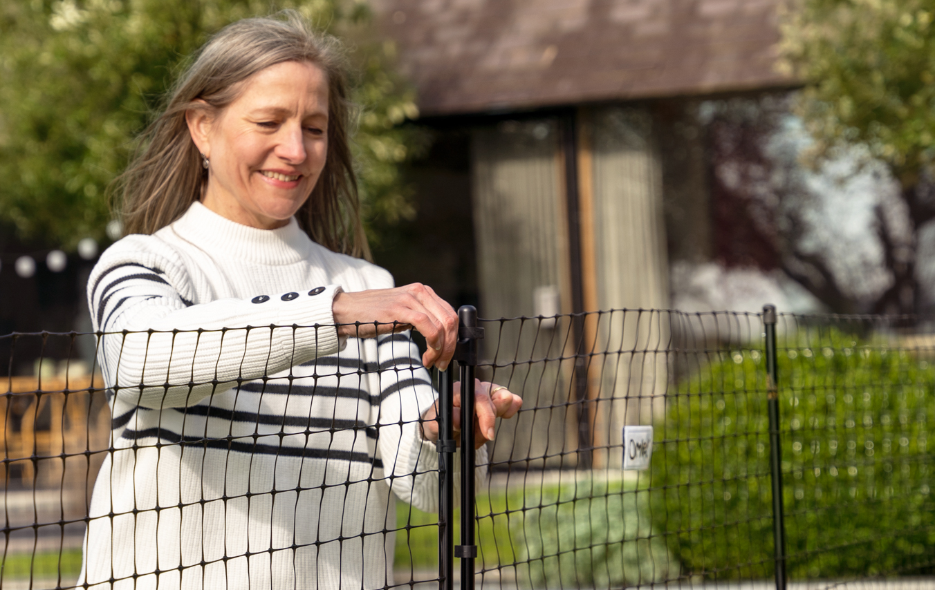 Donna che chiude il cancello della recinto per galline di Omlet